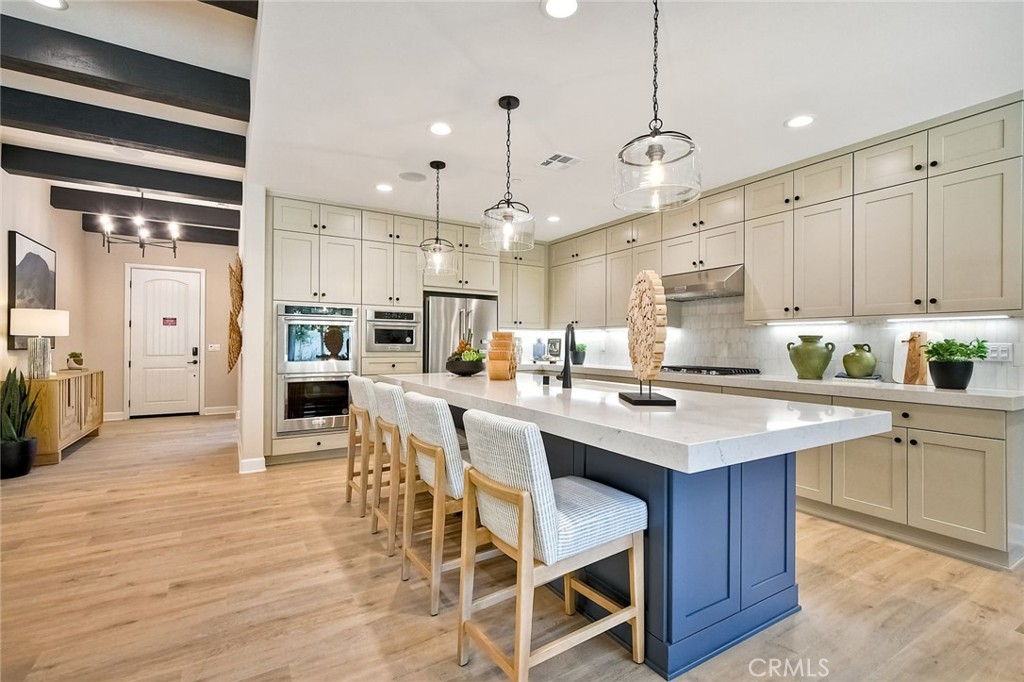 a kitchen with stainless steel appliances kitchen island granite countertop a table chairs sink and cabinets