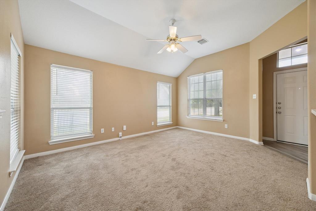 an empty room with chandelier fan and windows