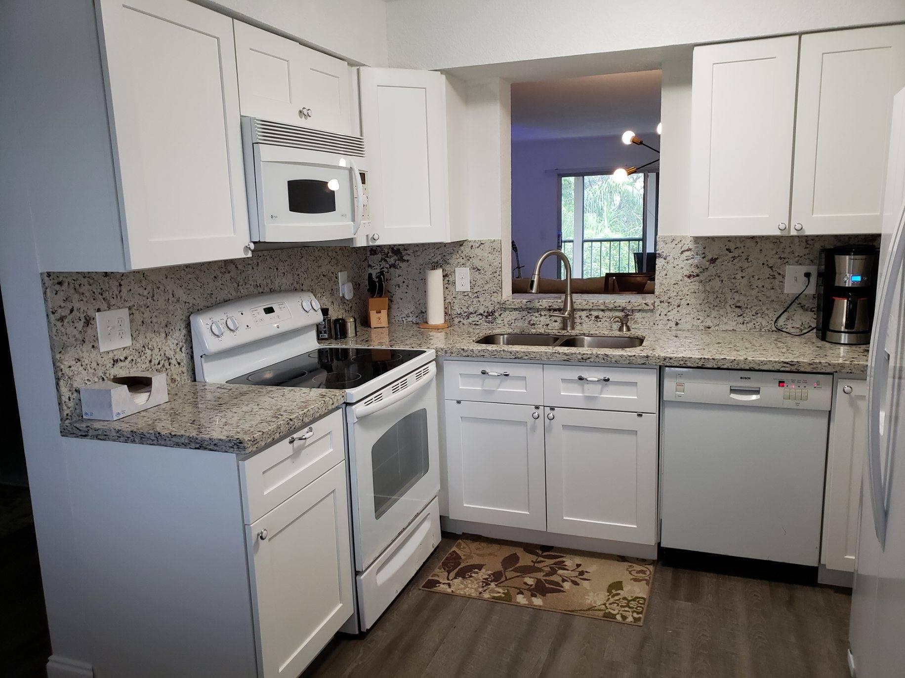 a kitchen with granite countertop cabinets stainless steel appliances and a wooden floor