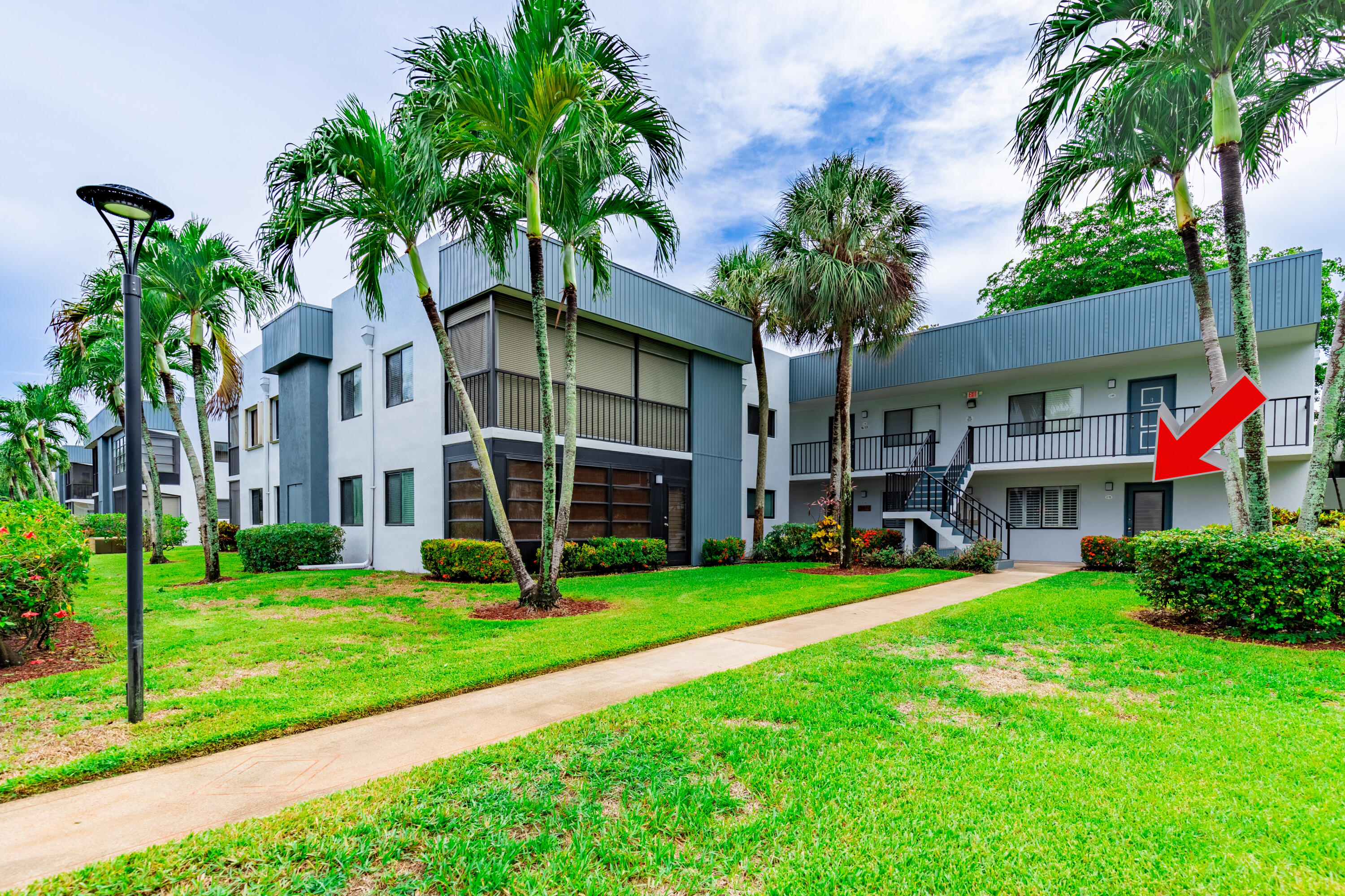 a view of an apartment with a garden and large trees