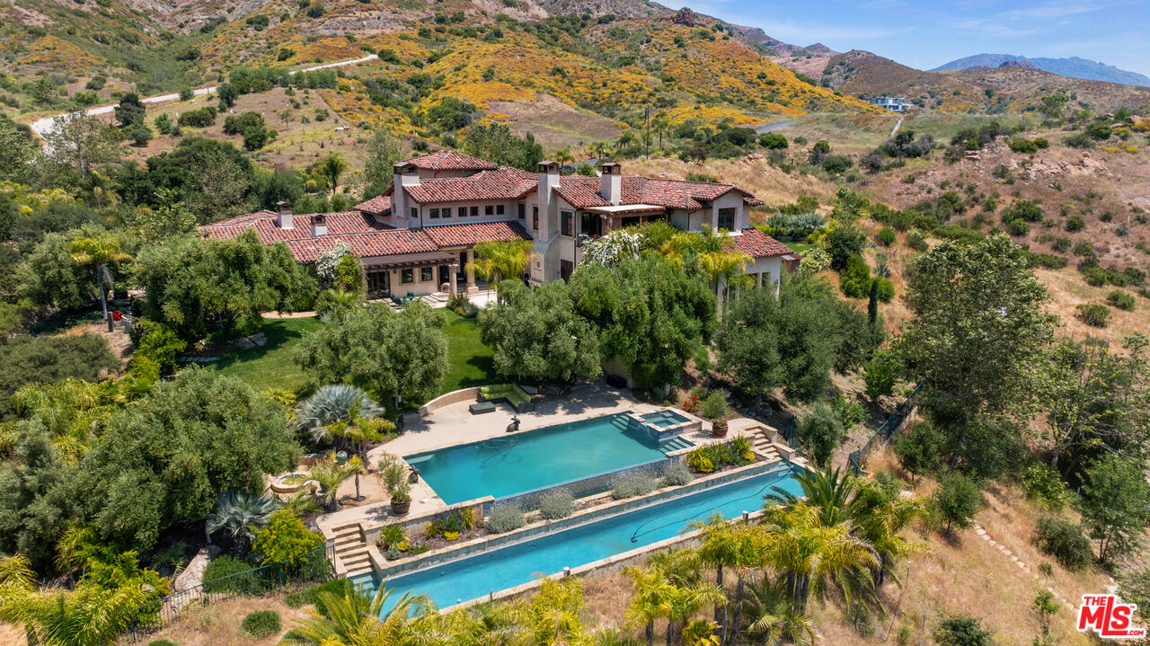 an aerial view of a house with a yard and mountain