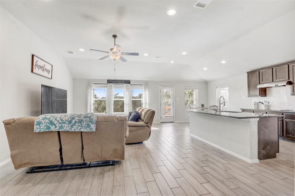 a living room with stainless steel appliances granite countertop furniture wooden floor and a kitchen view