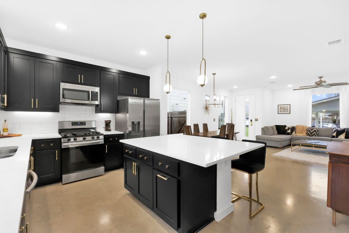 a large kitchen with stainless steel appliances kitchen island granite countertop a sink counter space and a center island