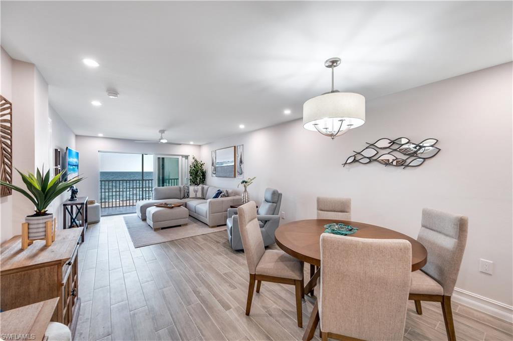 a dining room with wooden floor a chandelier fan a wooden table and chairs