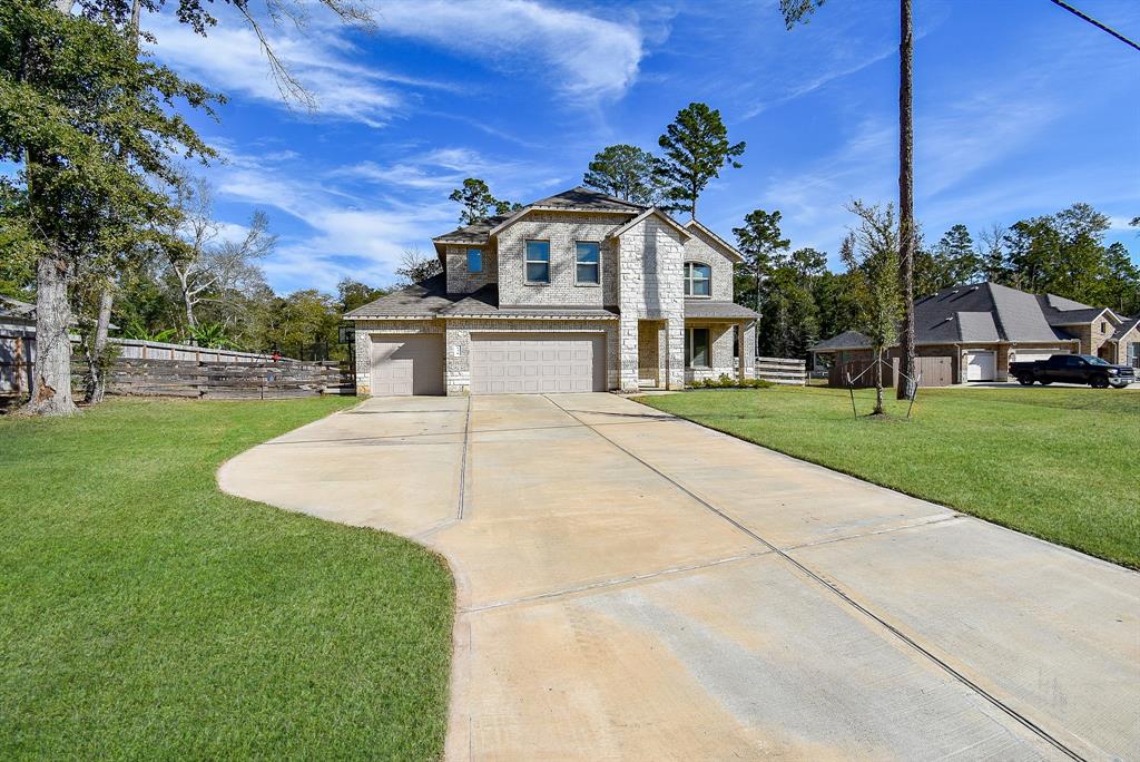 This photo shows a two-story stone house with a spacious driveway and a well-maintained lawn, set in a suburban neighborhood with mature trees.