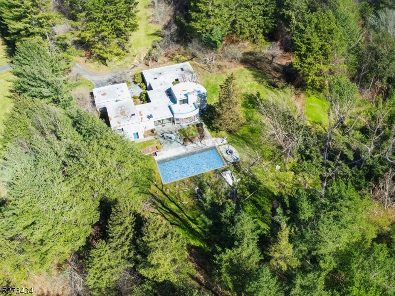 an aerial view of residential house with outdoor space and trees all around