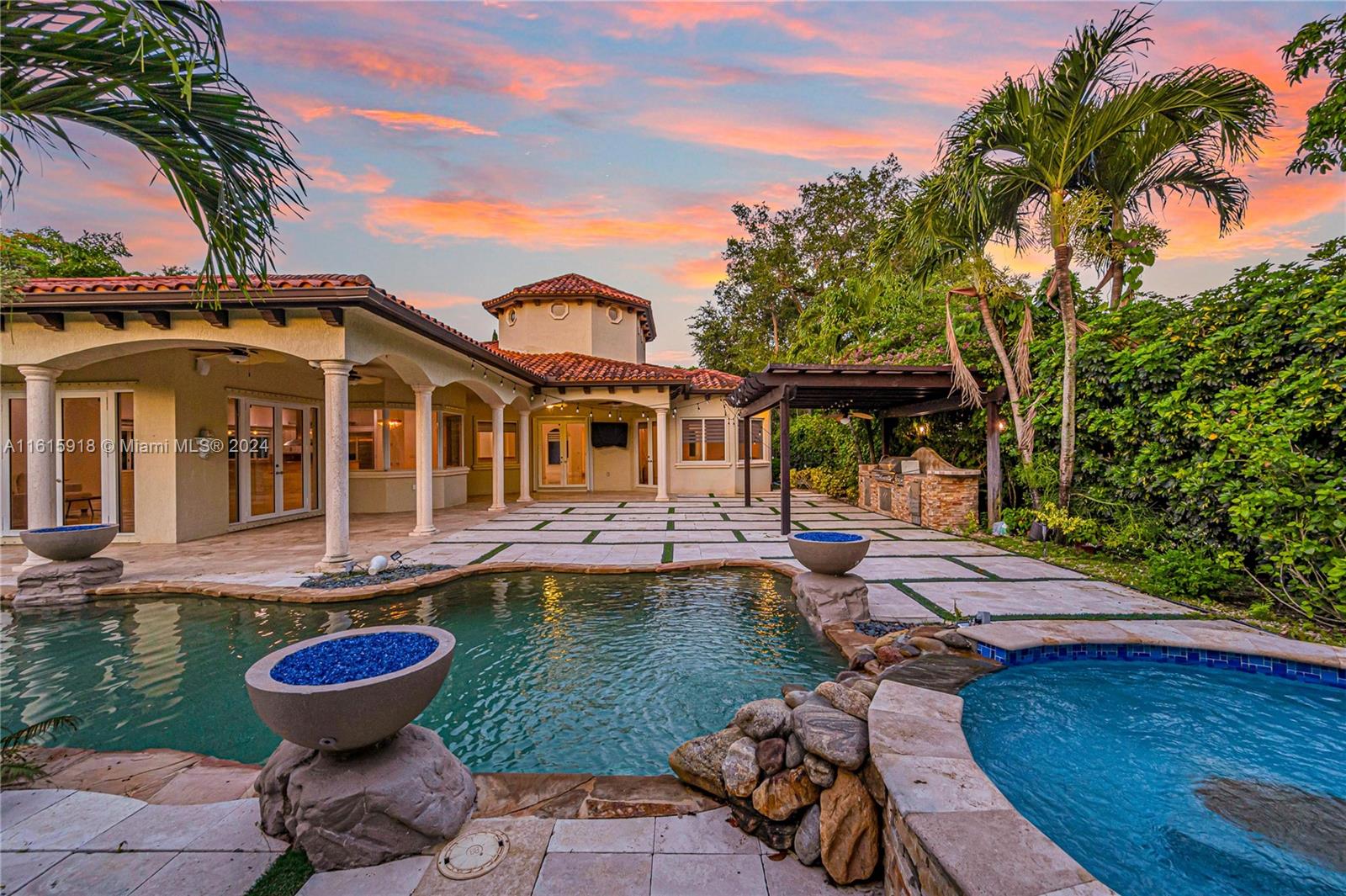 a view of a house with swimming pool lawn chairs and a fire pit