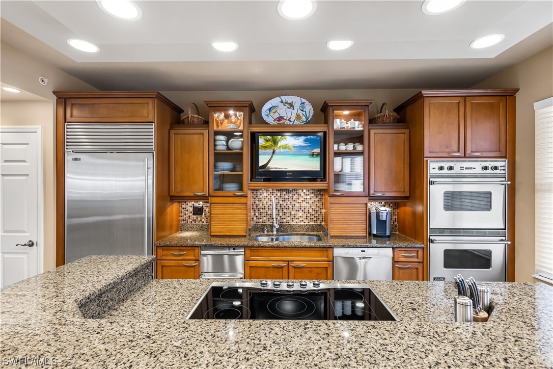 a kitchen with stainless steel appliances granite countertop a sink and a refrigerator