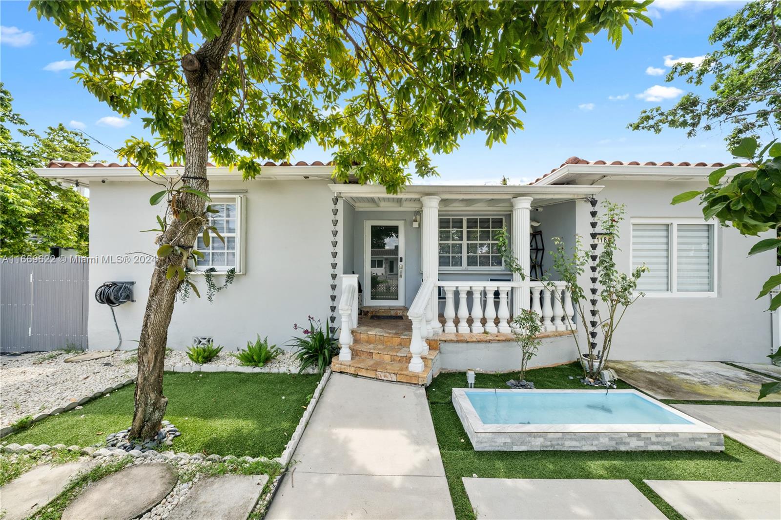 a view of a house with a small yard plants and large tree