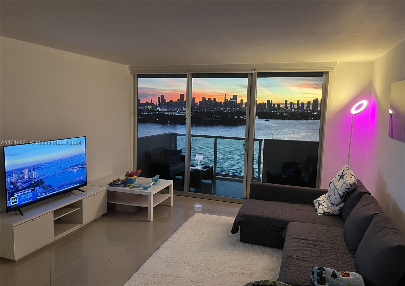 a living room with furniture a floor to ceiling window and a flat screen tv