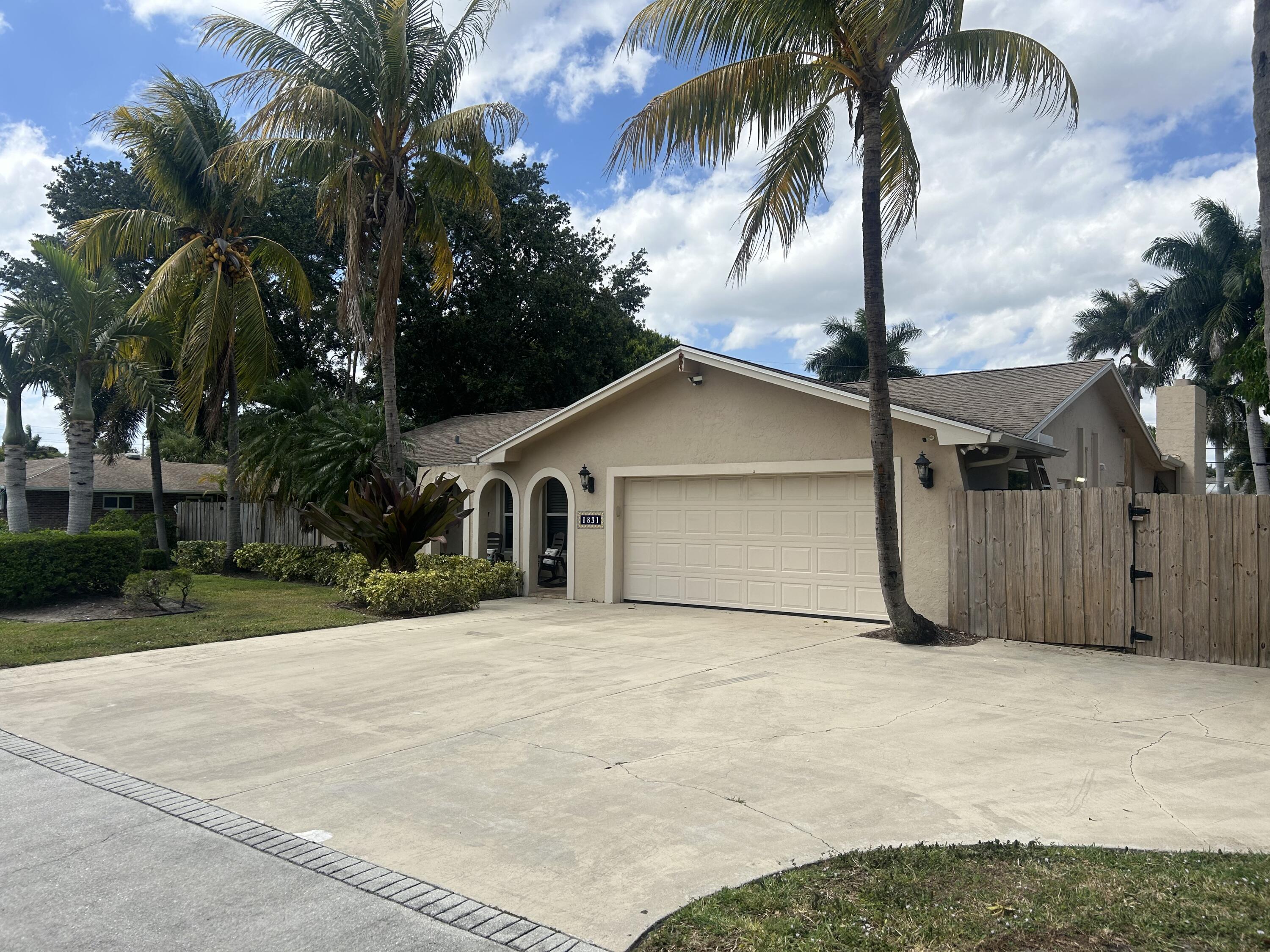 a view of a house with a yard and palm trees