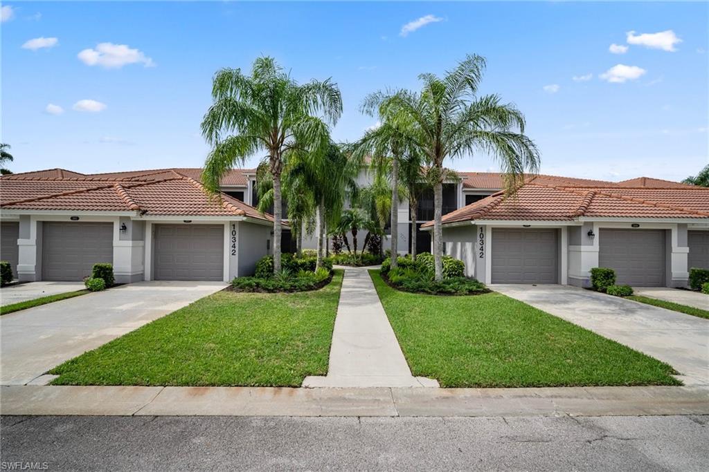 front view of a house with a yard and palm trees