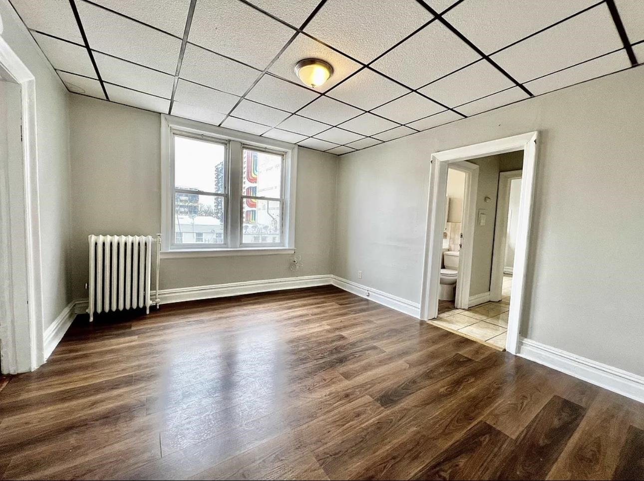 an empty room with wooden floor and windows