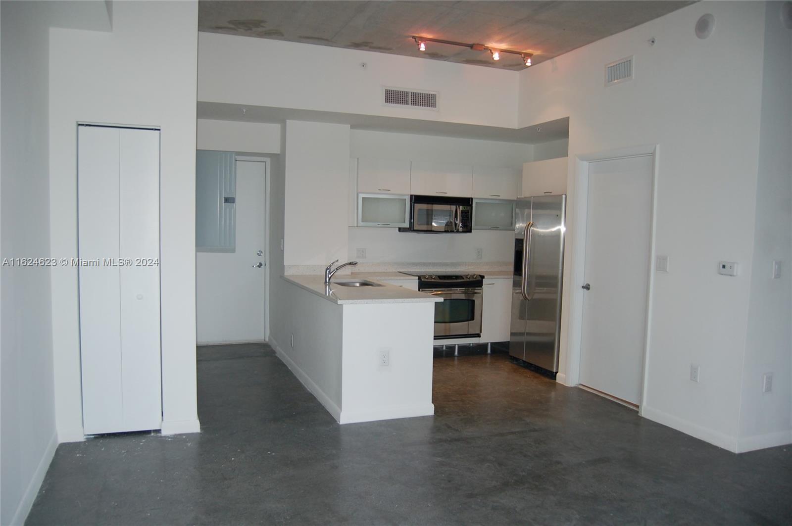 a view of a kitchen with refrigerator stove and cabinets