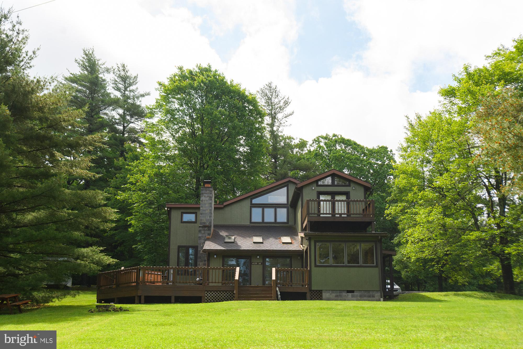 a view of a big house with a big yard and large trees