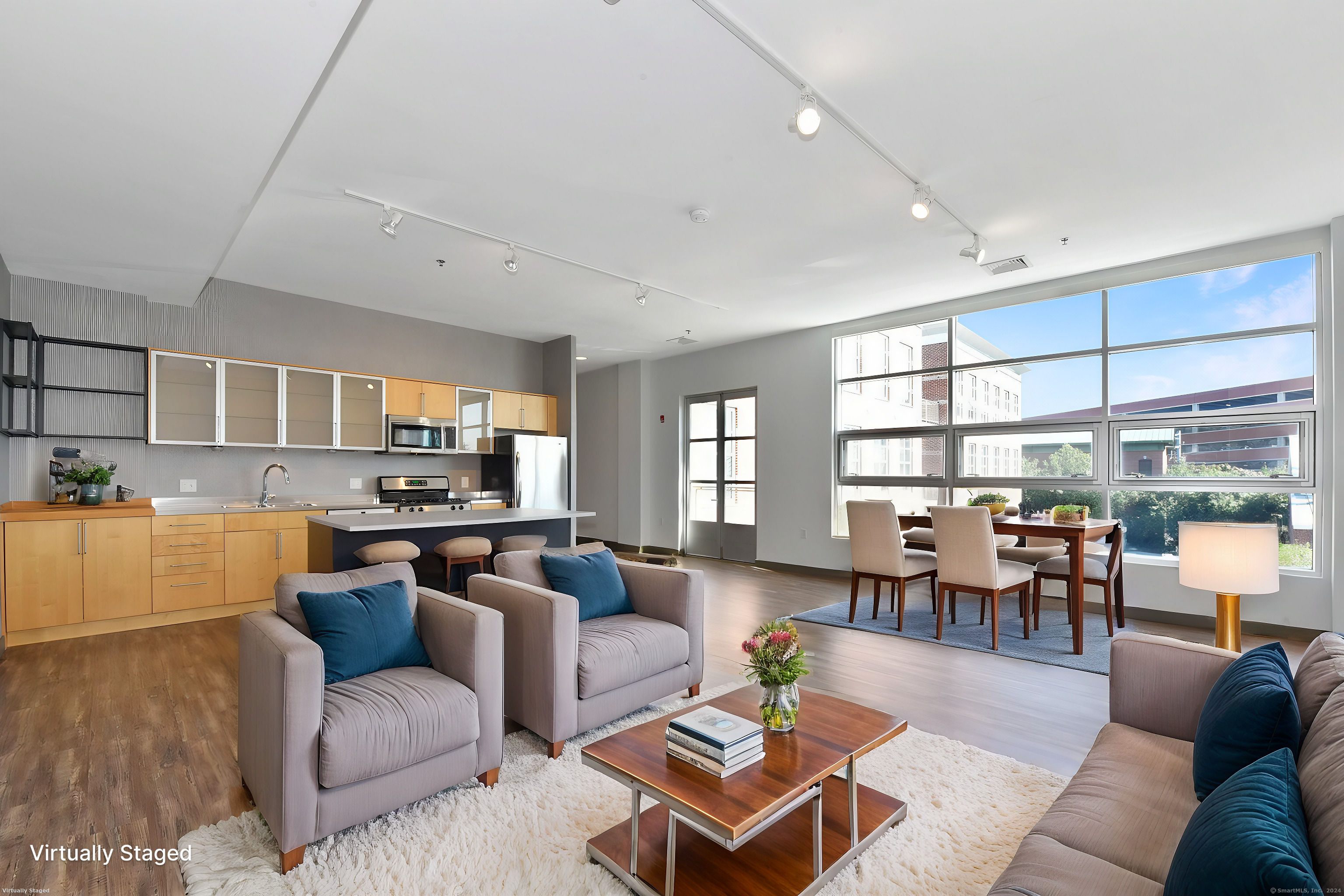 a living room with furniture kitchen view and a large window