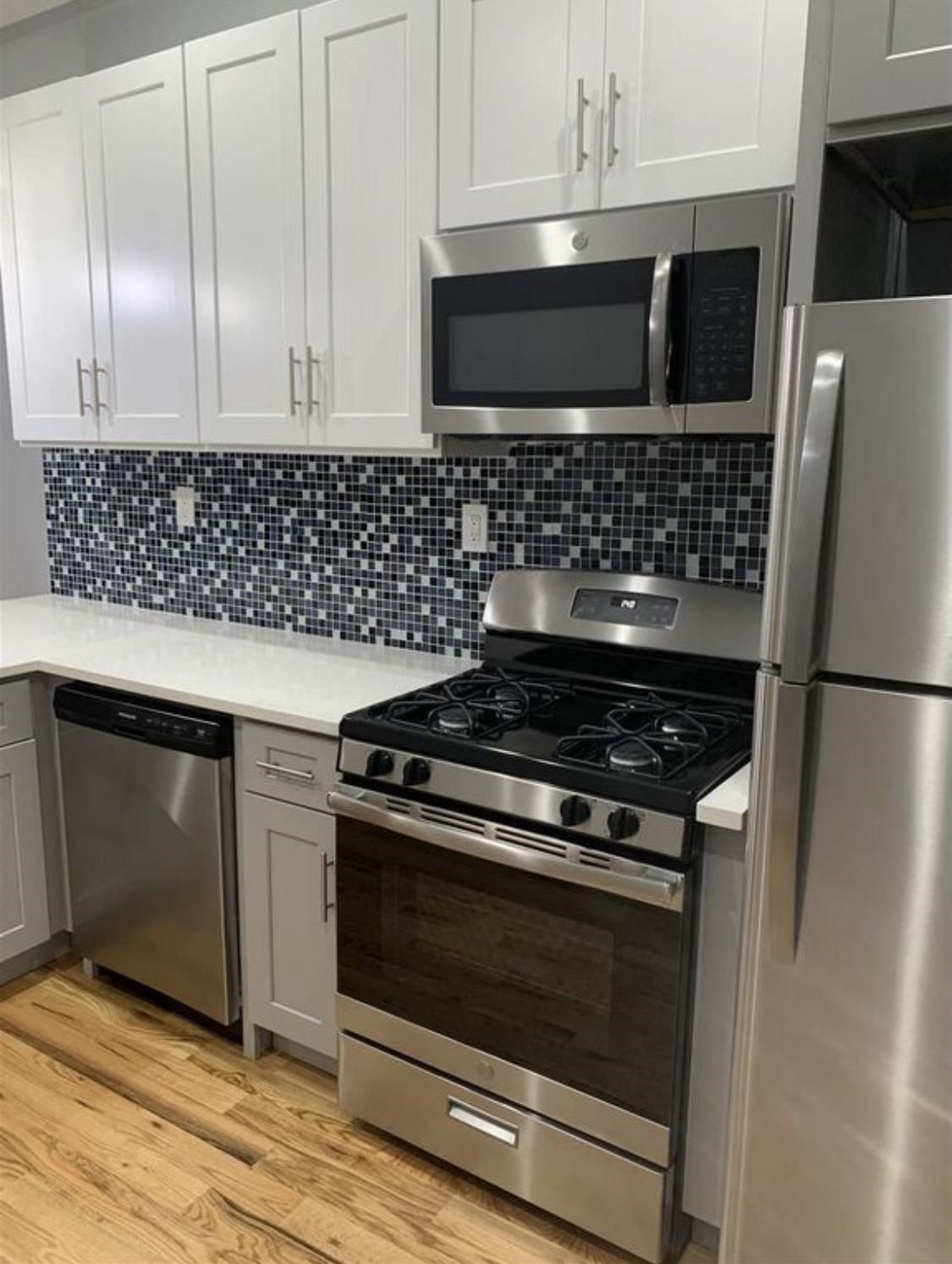 a kitchen with granite countertop white cabinets and stainless steel appliances