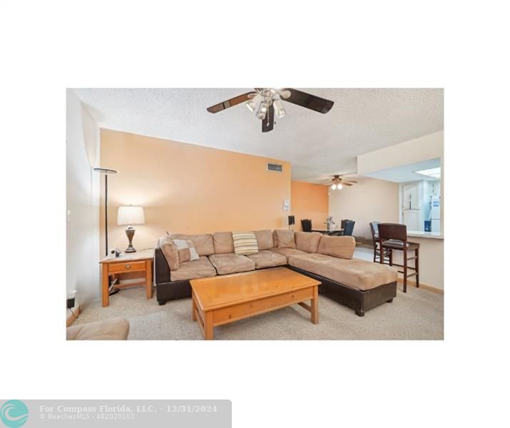 a living room with furniture and view of kitchen