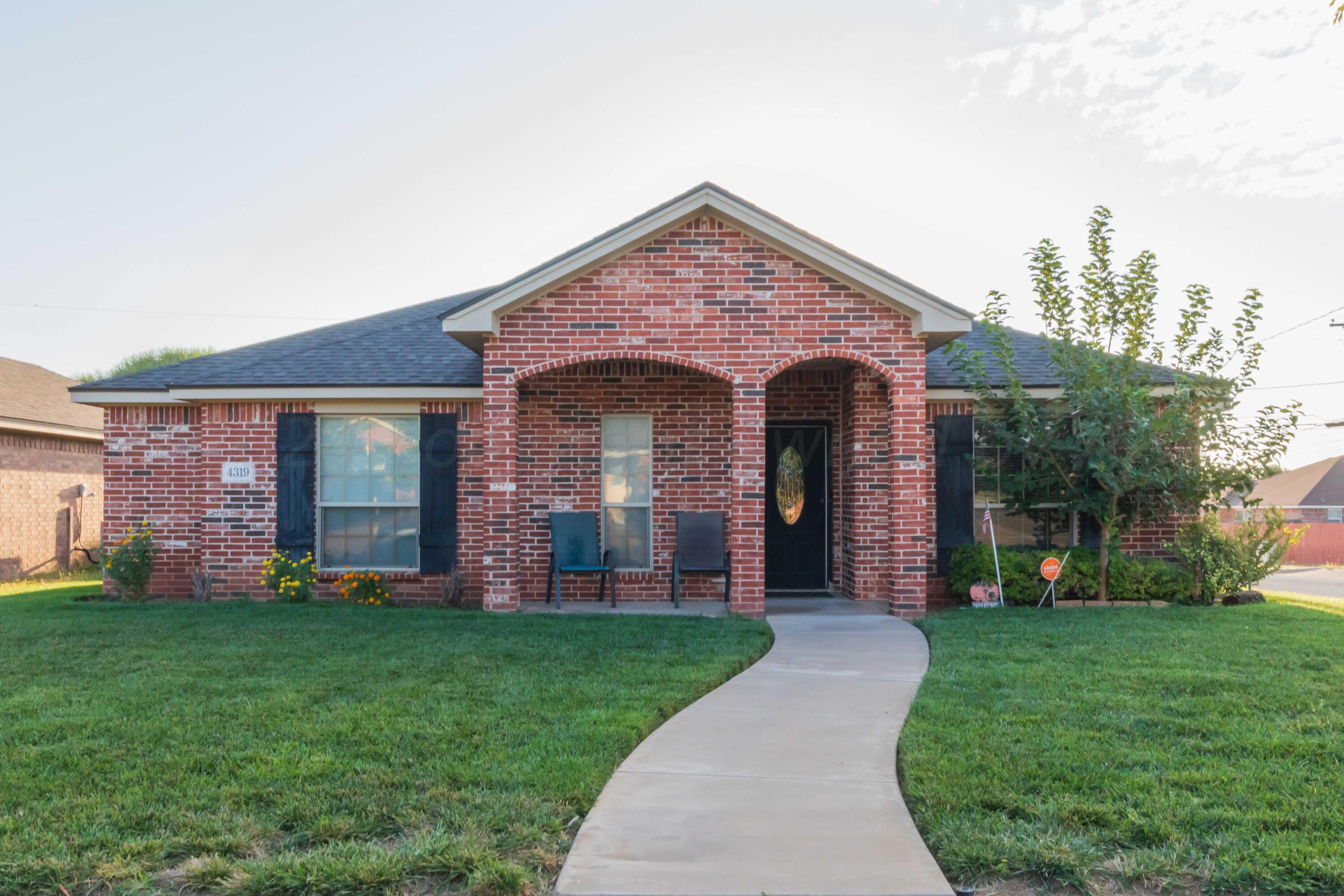 front view of a brick house with a yard