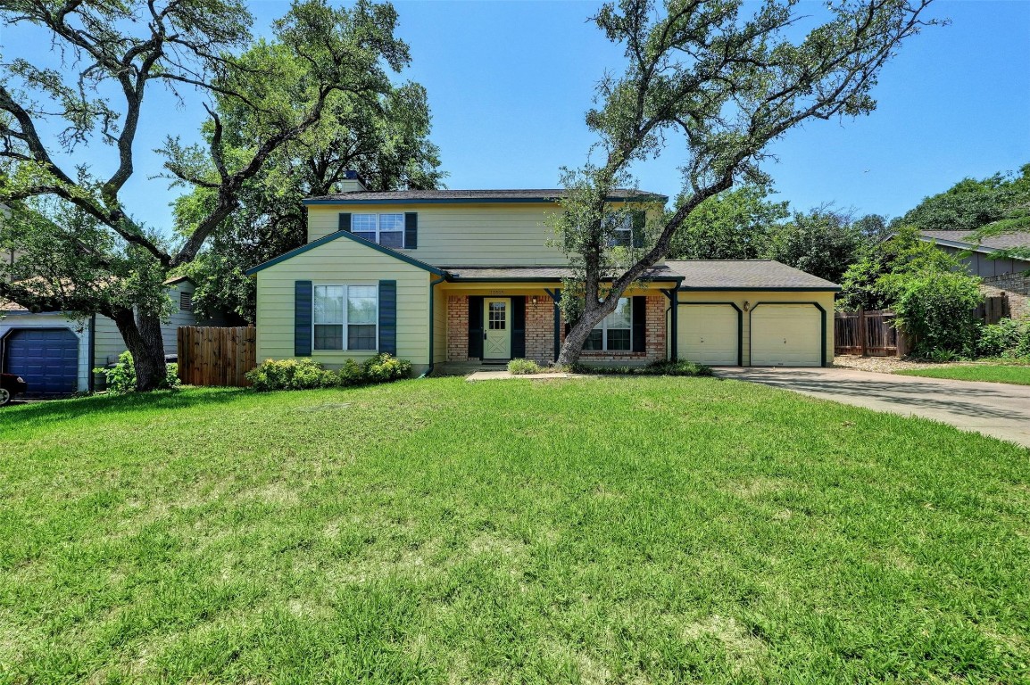 a front view of a house with a garden and trees