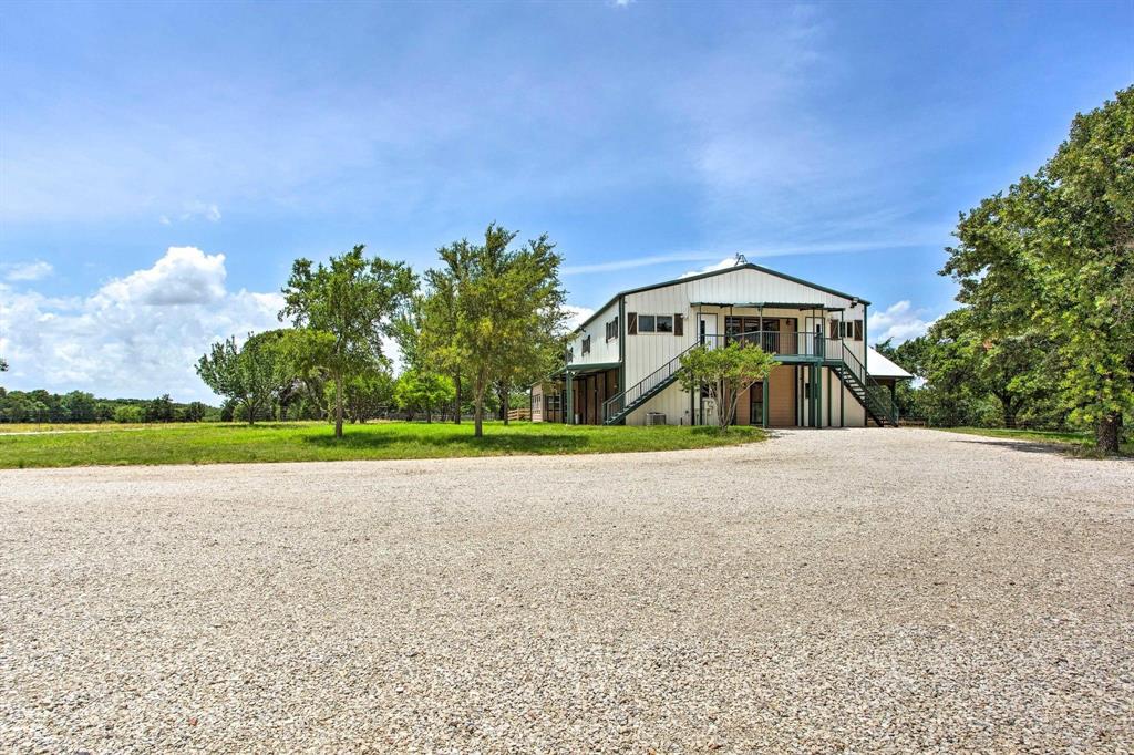 a view of a house with a yard and a large tree