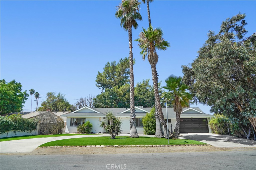 a front view of a house with a garden and trees