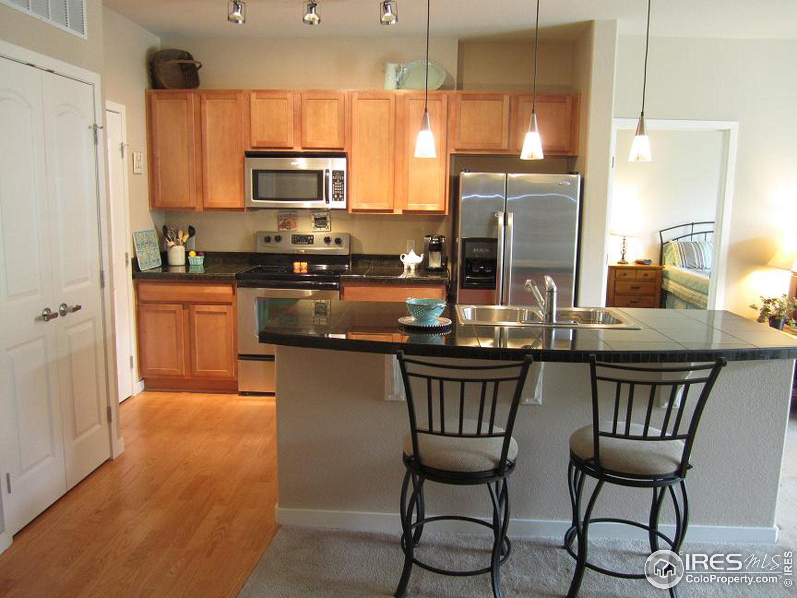 a kitchen with stainless steel appliances a stove a sink refrigerator and chairs