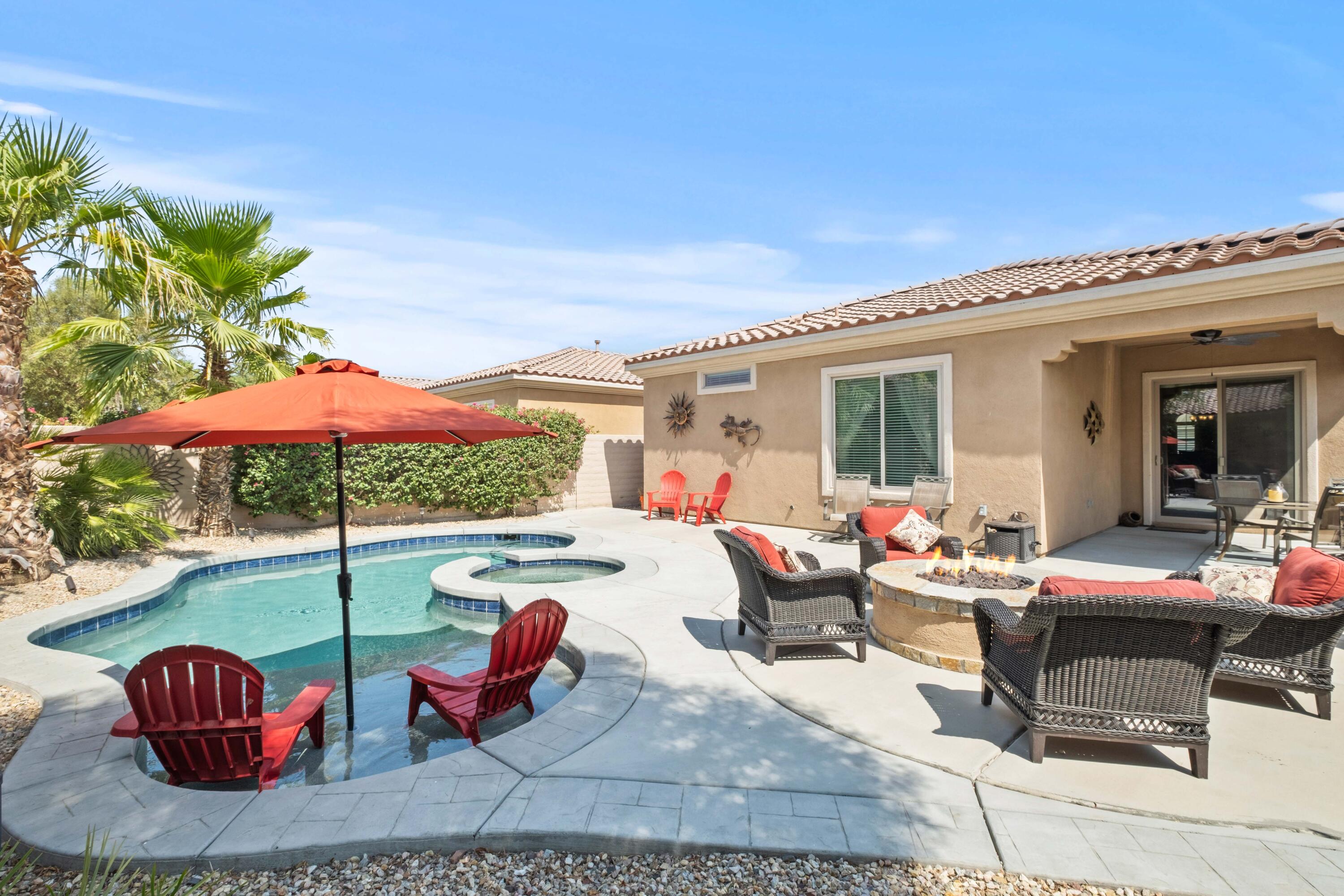 a view of a patio with couches table and chairs under an umbrella with barbeque grill and plants