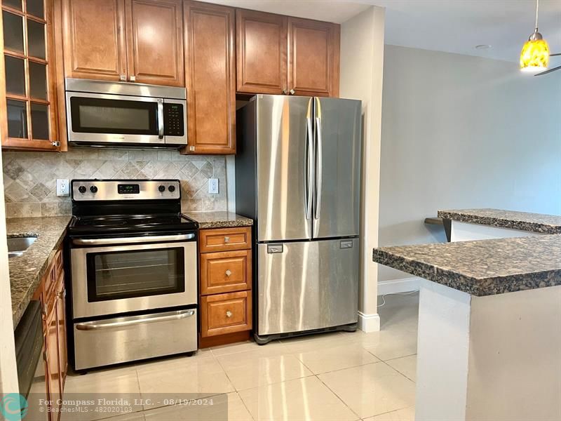 a kitchen with granite countertop a refrigerator stove and microwave