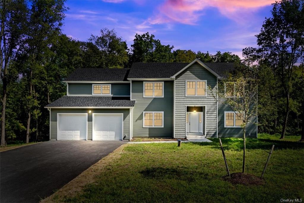 View of front facade featuring a garage and a lawn