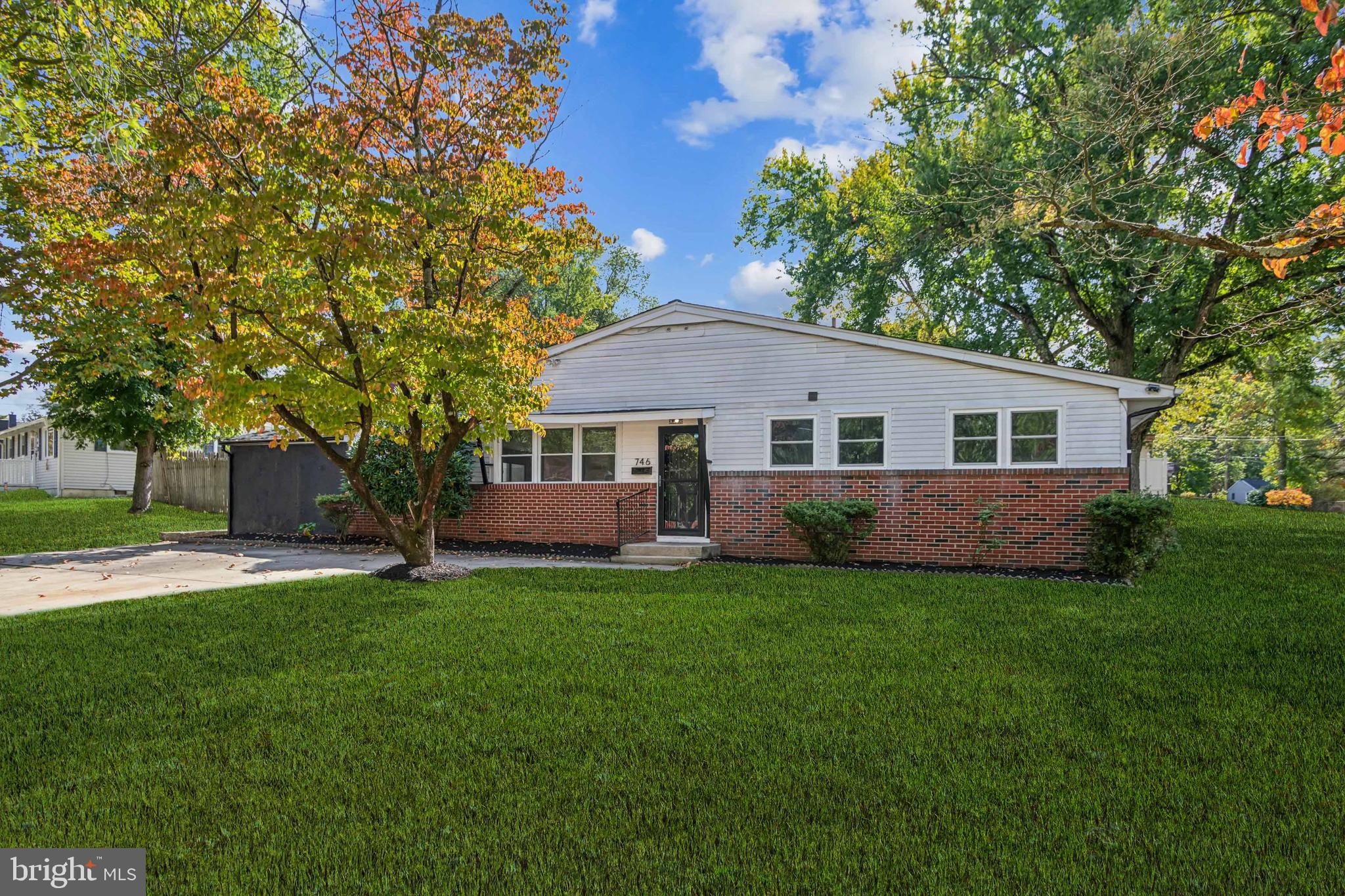 a front view of a house with a garden and trees