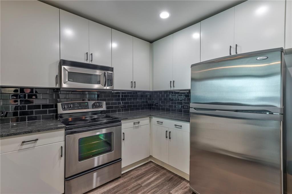 a kitchen with granite countertop a stove and a microwave with cabinets