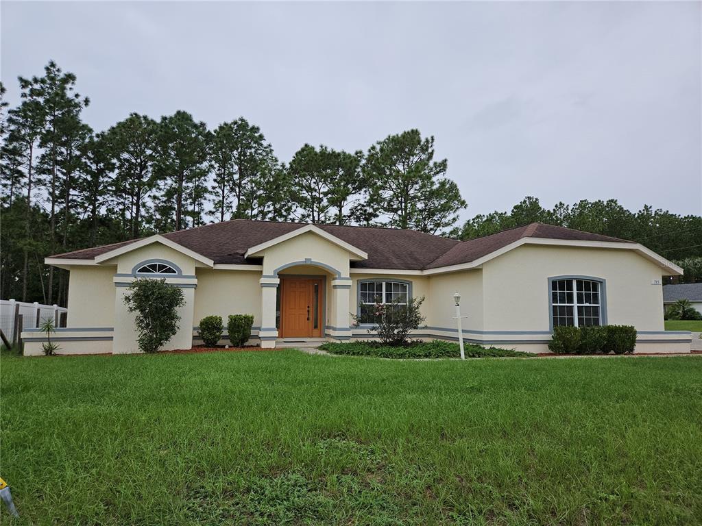 a front view of a house with a garden and trees