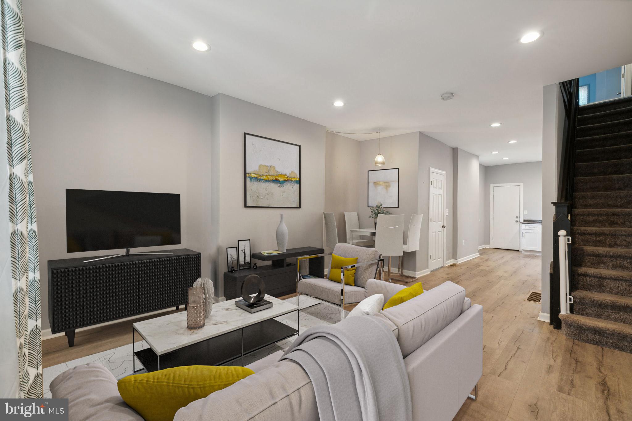 a living room with furniture a flat screen tv and kitchen view