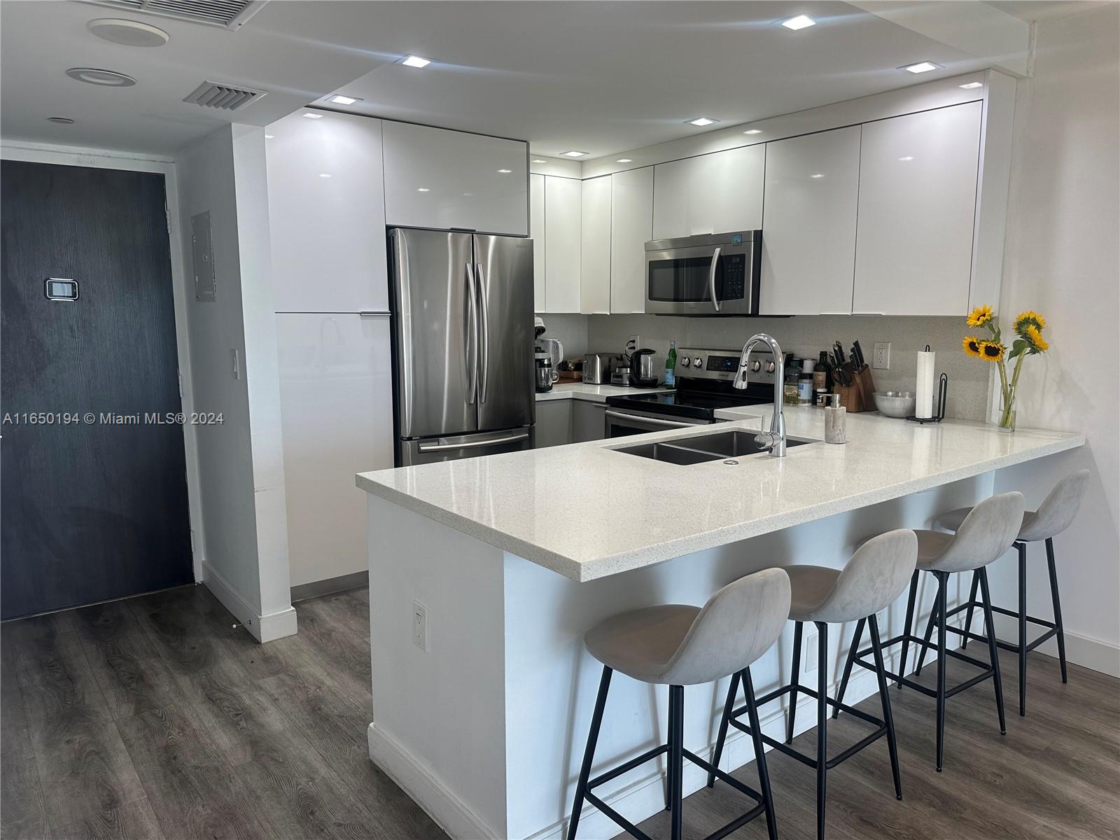 a kitchen with stainless steel appliances a kitchen island hardwood floor and a sink