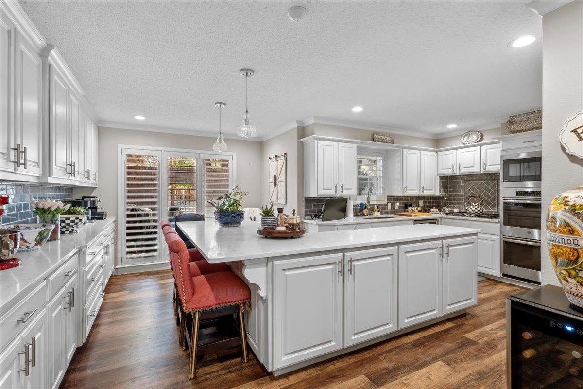 a kitchen with stainless steel appliances granite countertop a table chairs sink and cabinets