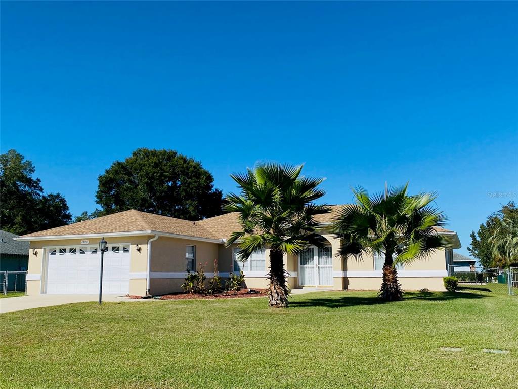 a view of a white house with a big yard and palm trees