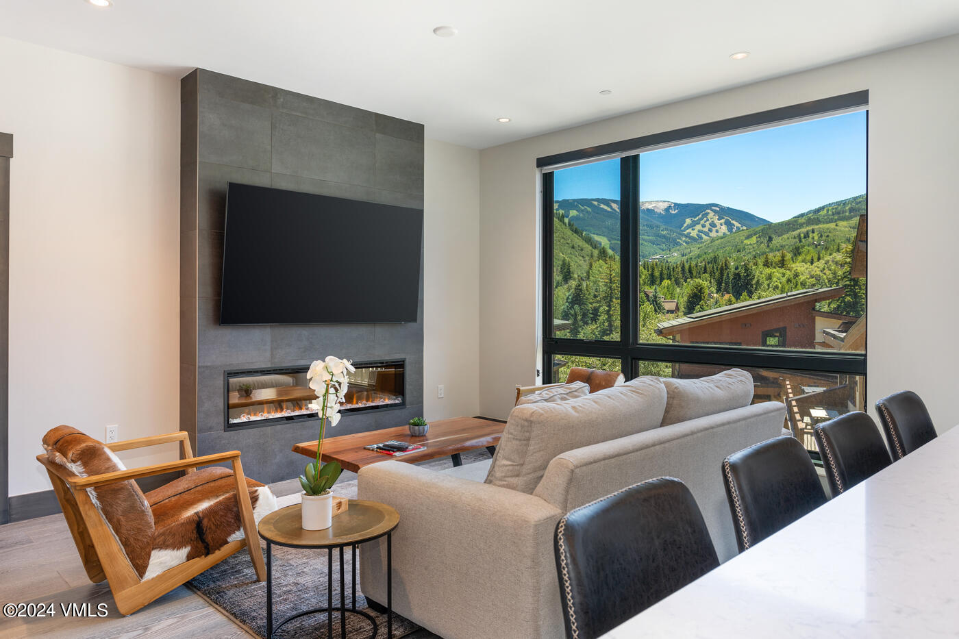 a living room with furniture a flat screen tv and a floor to ceiling window