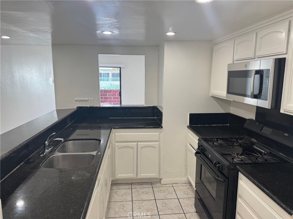 a kitchen with a sink and a stove top oven with wooden floor