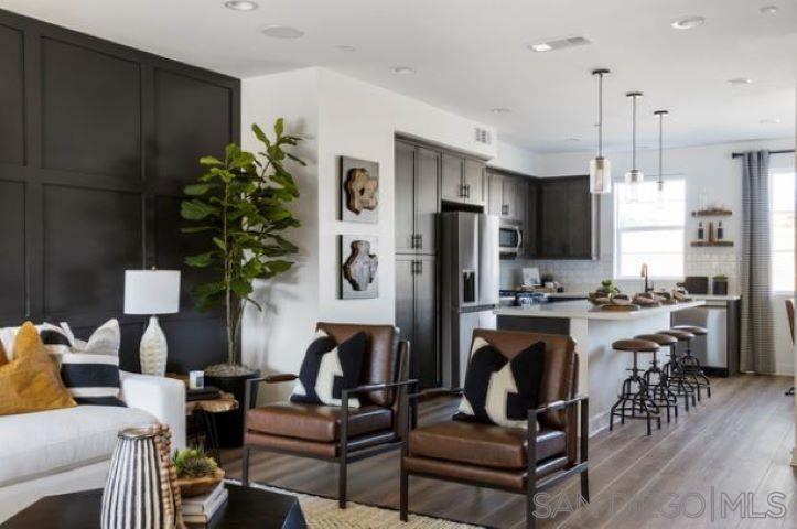 a living room with furniture a chandelier and kitchen view