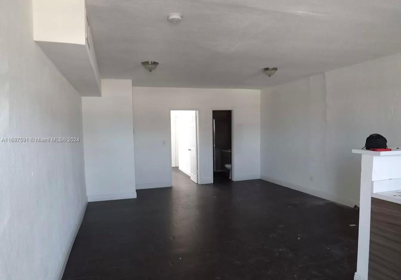 a view of an empty room with wooden floor and windows