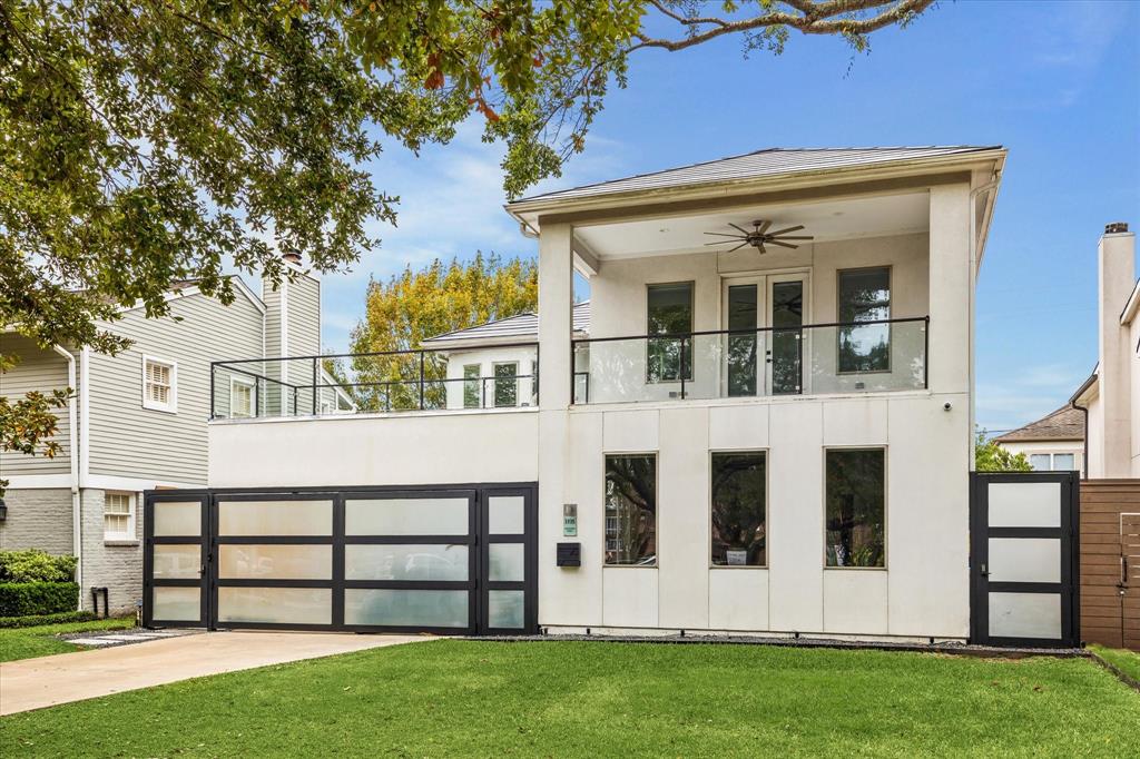 This striking modern home showcases sleek architectural lines, an expansive glass-panel privacy gate, and a spacious balcony overlooking a lush green lawn, offering a perfect blend of contemporary style and luxurious comfort.