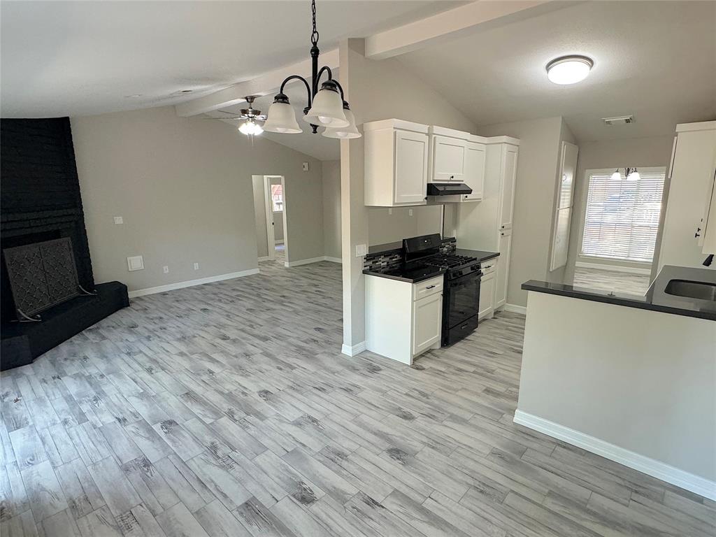 a kitchen with granite countertop a stove and a wooden floor