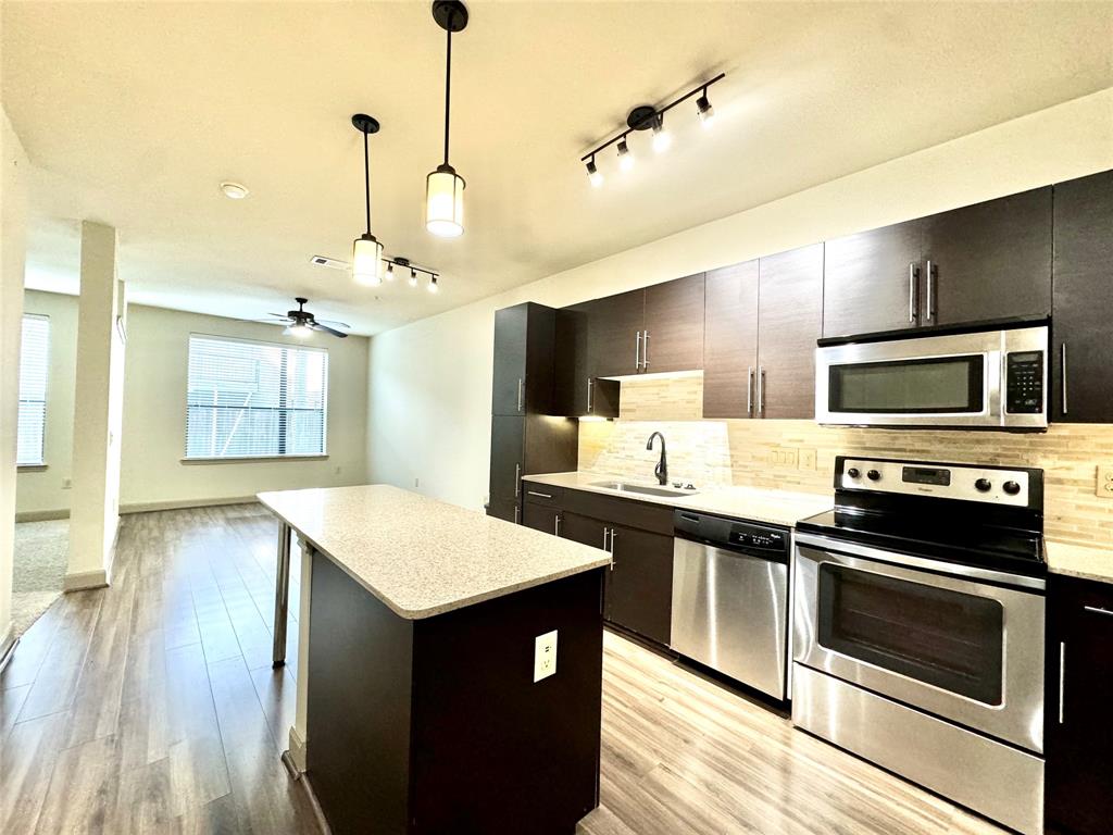 a kitchen with stainless steel appliances kitchen island a cabinets and wooden floor