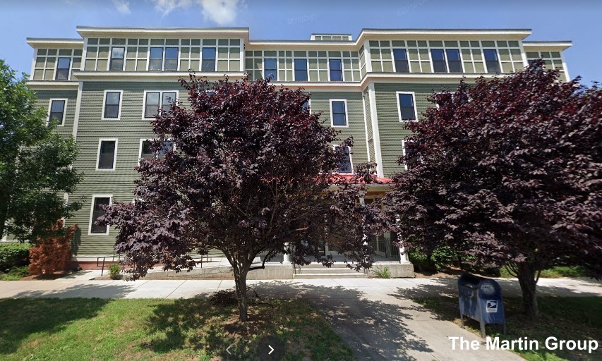 a front view of a building with a tree