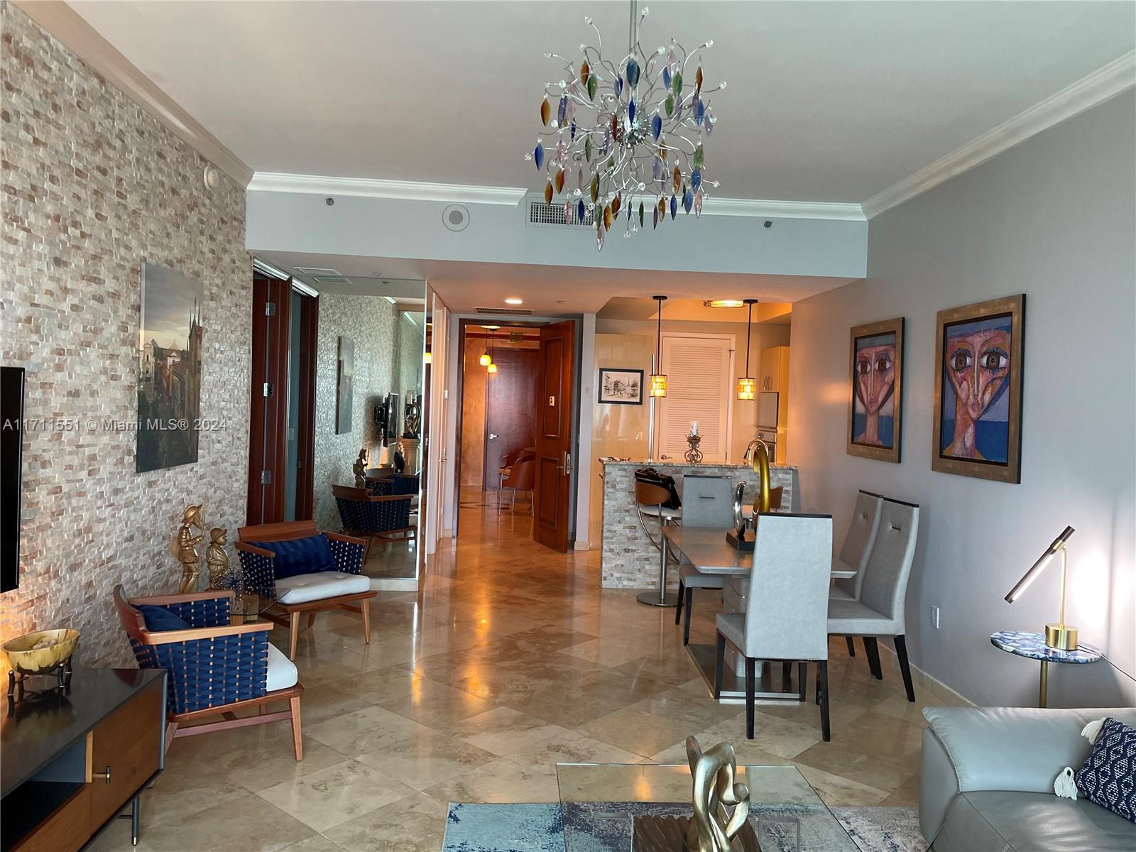 a dining room with wooden floor a chandelier a glass table and chairs