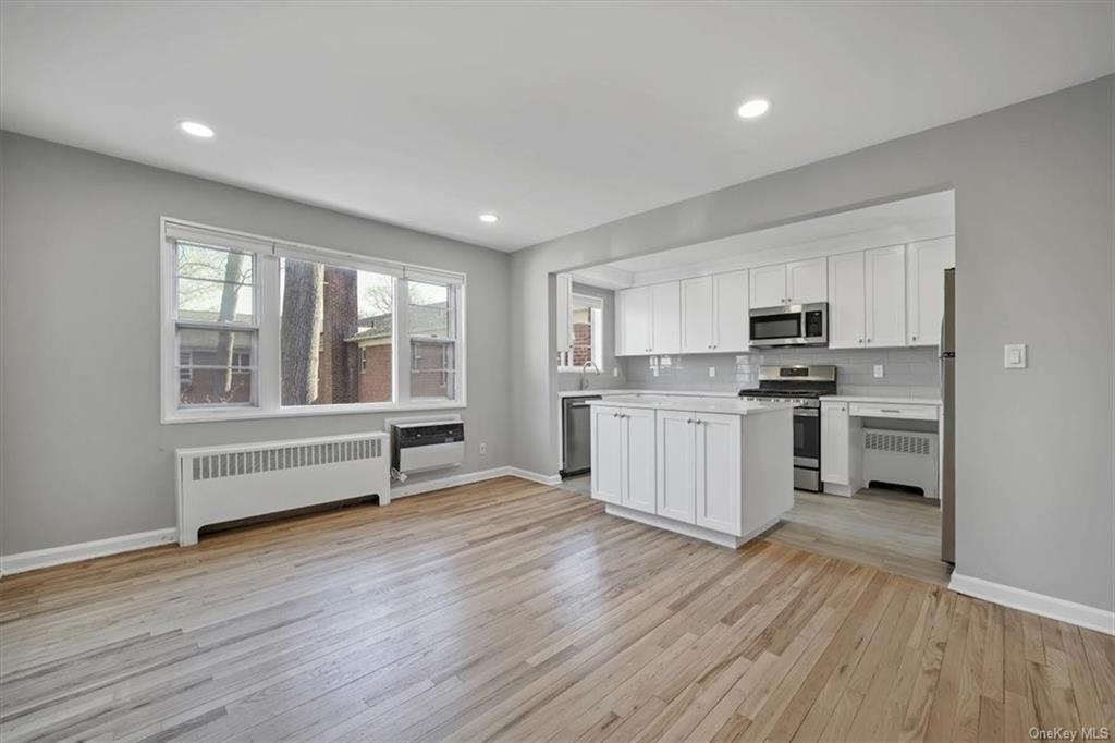 a kitchen with stainless steel appliances a white wooden cabinets and window