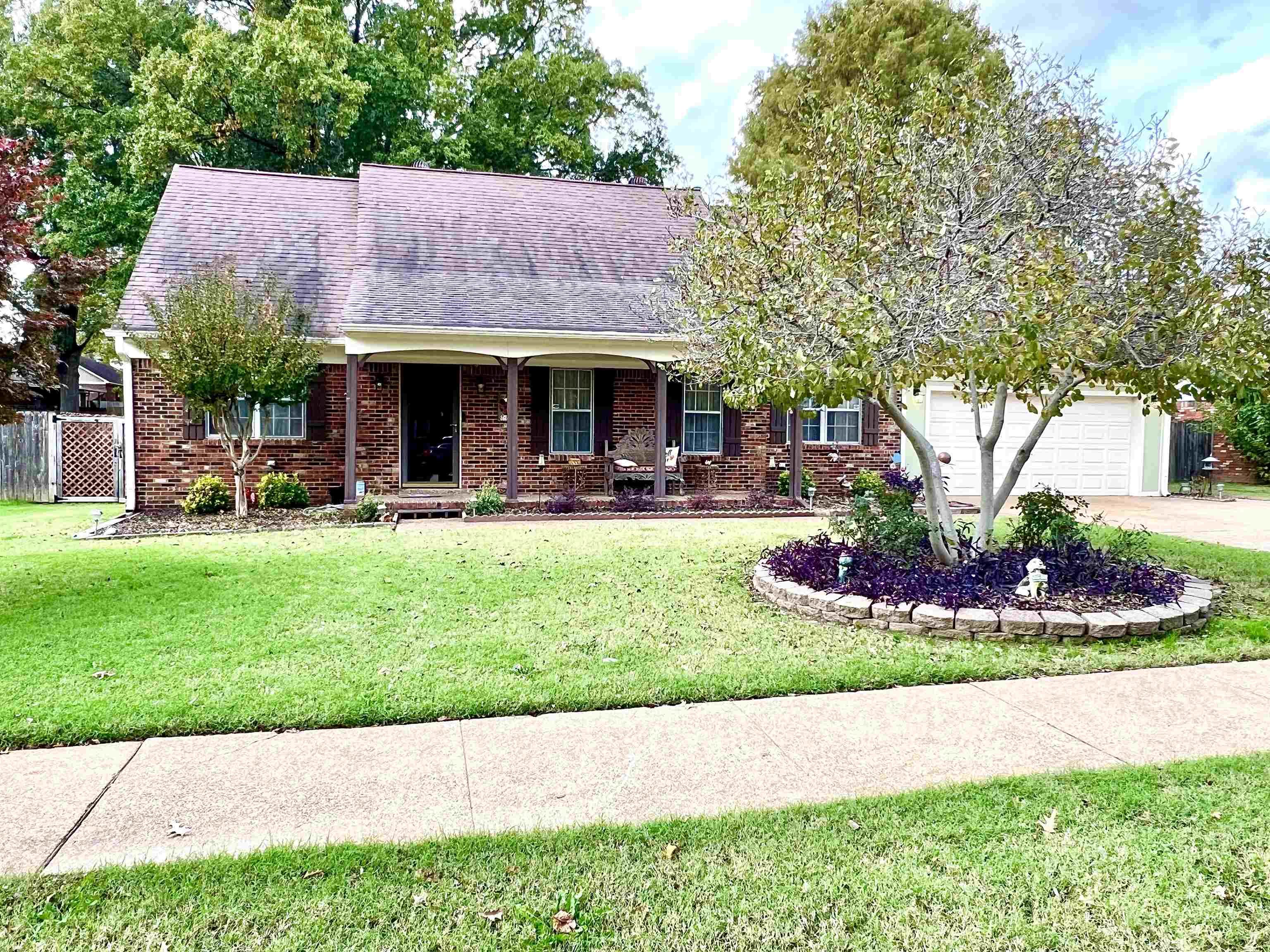 Ranch-style home featuring a front lawn, covered porch, and a garage