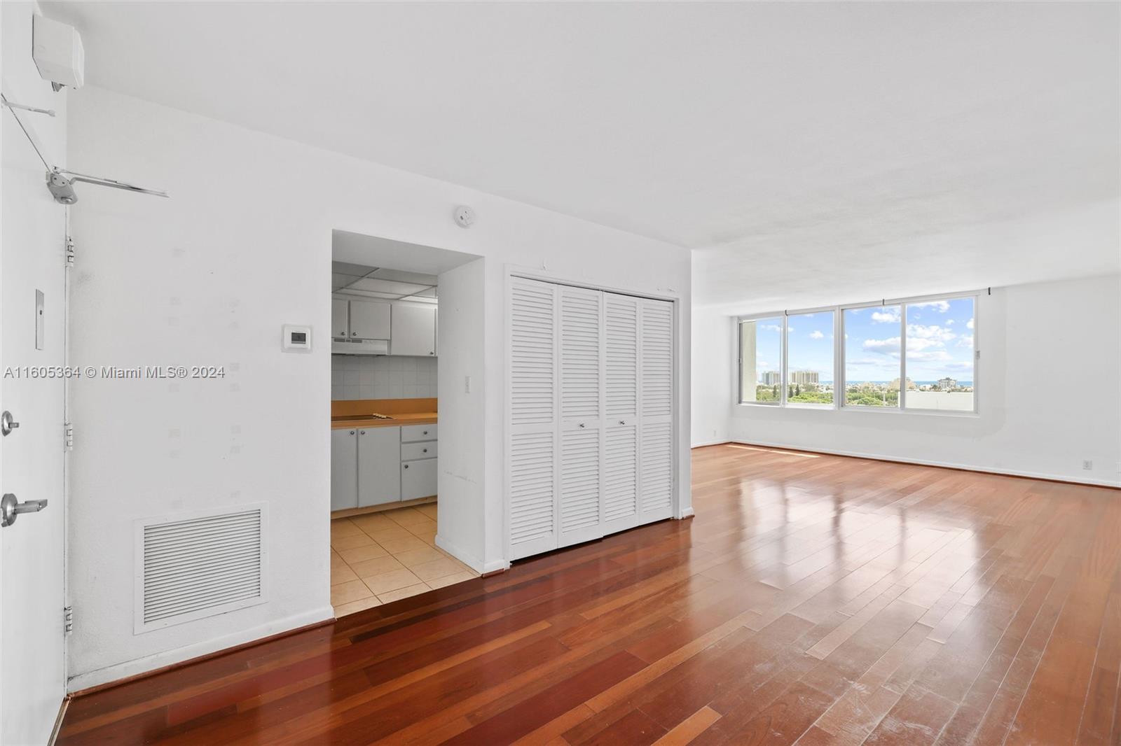 a view of an empty room with wooden floor and a window