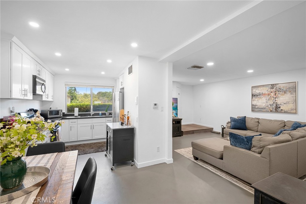 a living room with furniture and a dining table with kitchen view